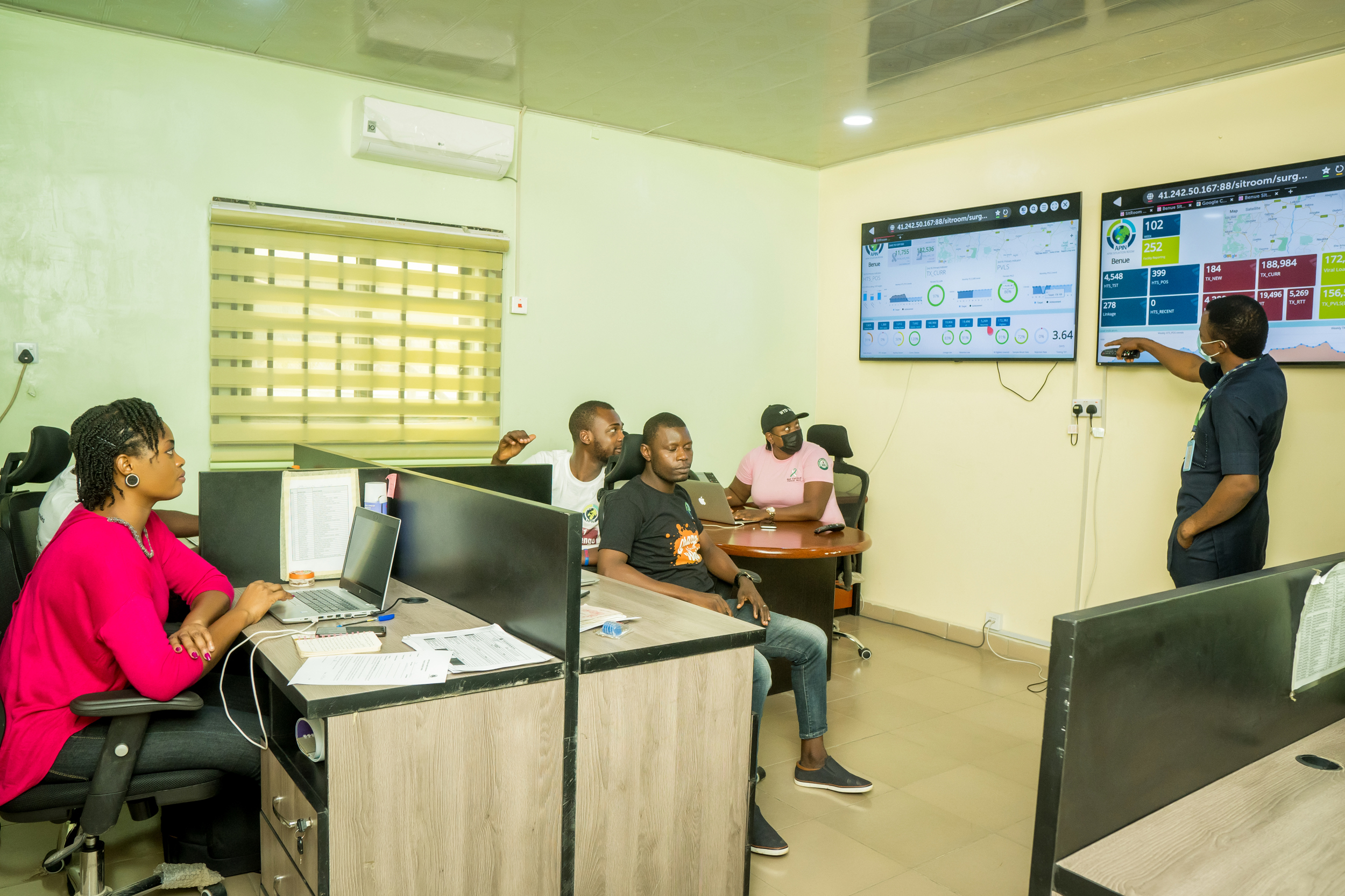 Public health team analysing real-time epidemiological metrics and health data on wall-mounted displays inside the Benue State Situation Room.