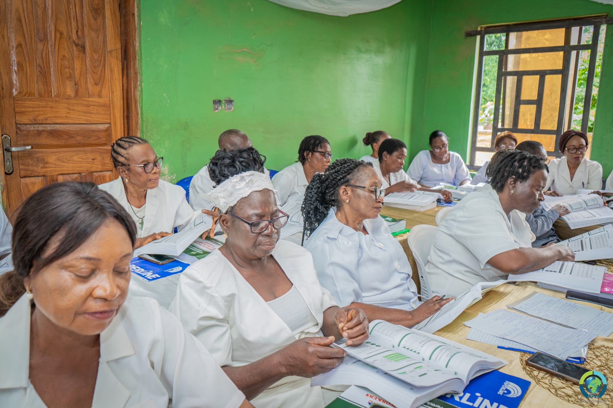 Healthcare workers and nurses participating in an APIN capacity-building training session studying clinical guidelines.